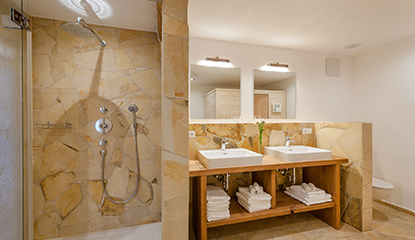 Ein Badezimmer mit Dusche und Waschbecken mit hellen Polygonalplatten gefliest