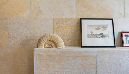 Eine mit sandfarbenen Platten geflieste Wand in einem Bad mit einem Bild und einem Dekorationselement