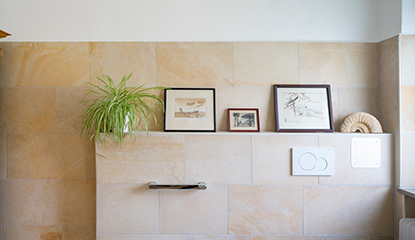 Eine mit sandfarbenen Platten geflieste Wand in einem band mit Bilder und Pflanzen