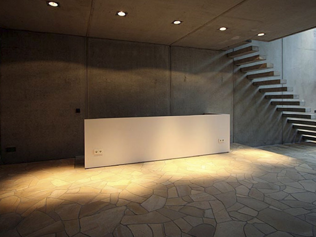 Ein Raum gepflastert mit Polygonalplatten während man im Hintergrund eine Treppe sieht