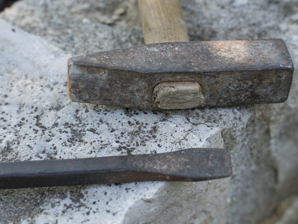 Ein Hammer liegt auf einer Mauer, die aus Mauersteinen aus Jura Marmor besteht