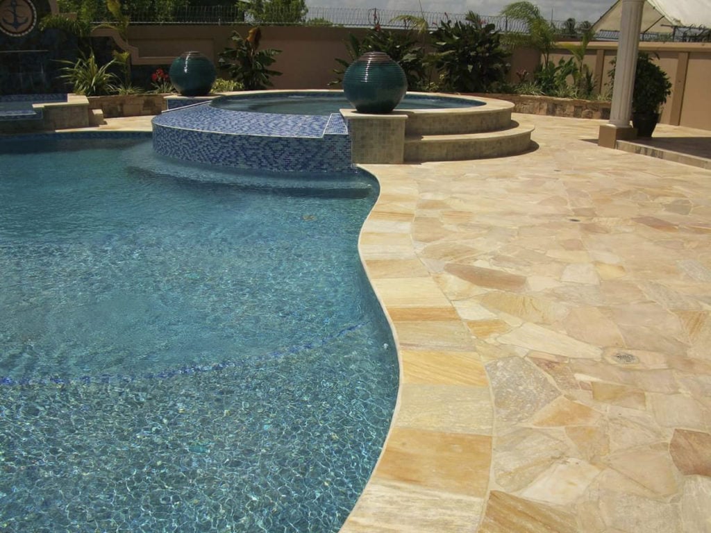 Ein mit sandfarbenen Polygonalplatten gepflasterter Pool