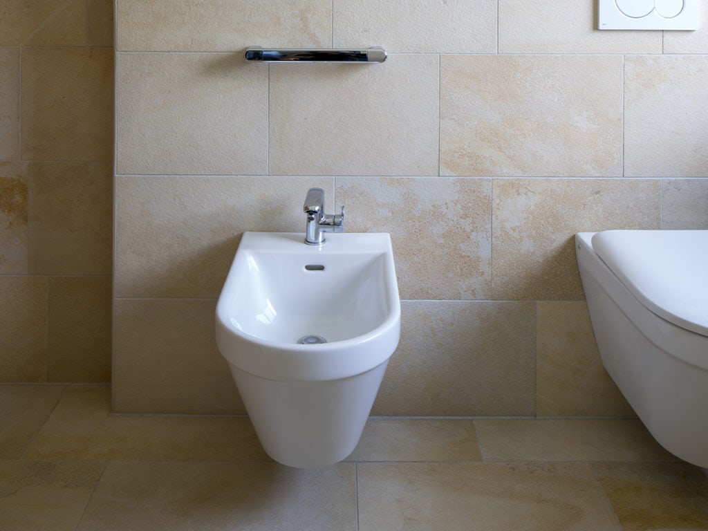 Ein mit hellen Bodenplatten gefliestes Badezimmer mit Bidet